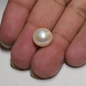 Pearl held between fingers on a white background